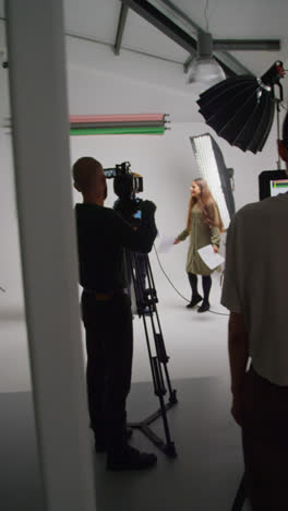 Vertical-Video-Of-Actors-With-Scripts-In-Rehearsal-Shooting-Movie-Or-Video-In-Studio-With-Female-Director-And-Film-Crew-And-Watching-On-Monitor-1